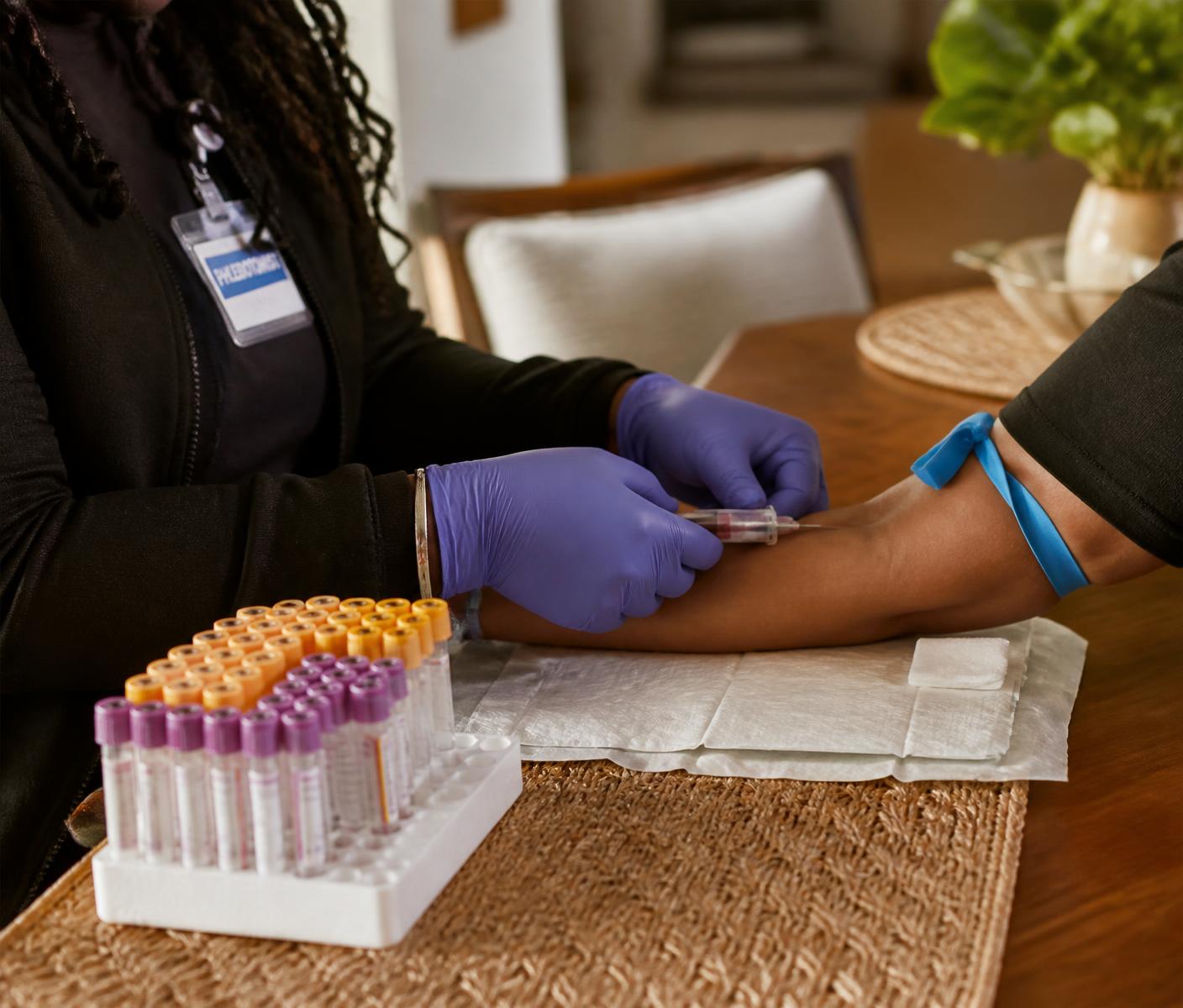Mobile phlebotomist drawing blood at a client's dining table